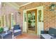 Charming brick porch with brick flooring, seating, front door, and decorative outdoor lighting at 10215 Balmoral Cir, Charlotte, NC 28210