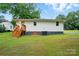 Exterior back view of the home featuring a well-maintained lawn and a set of wooden stairs at 107 S Branch St, Monroe, NC 28112