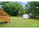 Large backyard with a storage shed, wooden fence, and a deck with stairs leading to the lawn at 107 S Branch St, Monroe, NC 28112