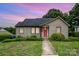 Charming bungalow featuring a well-kept lawn, beautiful landscaping, and eye-catching red front door, ideal for a starter home at 1125 Bethel Rd, Charlotte, NC 28208