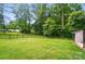 Spacious backyard with lush green grass, mature trees, and secure black metal fencing at 1209 Rainbow Dr, Kannapolis, NC 28081