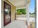 A cozy covered front porch with white columns, brick trim and mahogany front door at 1209 Rainbow Dr, Kannapolis, NC 28081