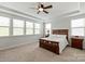 Relaxing bedroom featuring tray ceiling, three windows, and a wooden bed frame with side tables at 1244 Weir Ct, Fort Mill, SC 29708