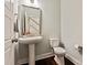 Well-lit powder room with hardwood floors, toilet, pedestal sink, and large mirror at 1244 Weir Ct, Fort Mill, SC 29708