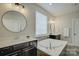 Luxurious bathroom with a soaking tub, dual sinks, white countertop, and modern fixtures at 15344 Cimarron Hills Ln, Charlotte, NC 28278