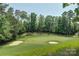 Scenic view of the golf course with lush green fairways, mature trees, and sand traps under a bright sky at 15344 Cimarron Hills Ln, Charlotte, NC 28278