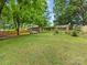Expansive backyard features lush green grass, mature trees, a garden, and picnic areas, perfect for outdoor living at 3042 Cresthill Dr, Charlotte, NC 28212
