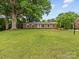 Traditional brick home featuring a sprawling green lawn, classic design, and mature trees at 3042 Cresthill Dr, Charlotte, NC 28212