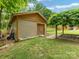 Exterior view of a shed featuring wood paneling, a brick walkway, and lush landscaping at 3042 Cresthill Dr, Charlotte, NC 28212