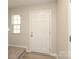 Bright entryway with light-colored walls, a white door, and carpeted stairs leading to the upper level at 3349 Ellingford Rd, Charlotte, NC 28214