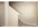 A simple staircase with carpeted steps and a white handrail against a light-colored wall at 3349 Ellingford Rd, Charlotte, NC 28214