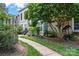 Charming townhouse exterior with lush greenery, walkway, and a porch swing, offering a welcoming curb appeal at 3520 Colony Rd # D, Charlotte, NC 28211