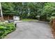 Expansive paved backyard with a basketball court, storage shed, and lush green surroundings at 3624 Moultrie St, Charlotte, NC 28209