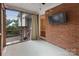 Brick-walled screened porch features an exterior mounted TV and backyard views at 3624 Moultrie St, Charlotte, NC 28209