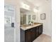 Bathroom featuring double sinks with granite counters, dark cabinets, and a large mirror at 4732 Water Oak Rd, Charlotte, NC 28211