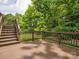 Spacious wooden deck with stairs overlooking a lush, green backyard with mature trees at 5805 Copperleaf Commons Ct, Charlotte, NC 28277