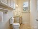 Powder room featuring a toilet, vanity, sink, and window, perfect for guests and everyday convenience at 5805 Copperleaf Commons Ct, Charlotte, NC 28277