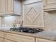 Close-up of the gas cooktop, custom backsplash, and granite counters in the updated kitchen at 5805 Copperleaf Commons Ct, Charlotte, NC 28277