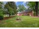 Large brick house with a manicured lawn, mature trees, and a fire pit at 5926 Sharon Rd, Charlotte, NC 28210