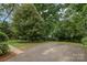 Backyard with a parking pad, green grass, and mature trees at 5926 Sharon Rd, Charlotte, NC 28210