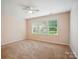 Spacious bedroom with neutral carpet, ceiling fan and three windows bringing in natural light at 6007 Edinburgh Ln # 214, Indian Land, SC 29707