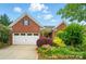 Charming brick home with a two-car garage and beautifully landscaped front yard featuring vibrant flowers and greenery at 6007 Edinburgh Ln # 214, Indian Land, SC 29707