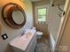 Bathroom with round wood mirror, white vanity, tub, and window for natural light at 8095 New St, Mount Pleasant, NC 28124