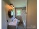 Bathroom features a vanity with a round mirror, natural light and a tub at 8095 New St, Mount Pleasant, NC 28124