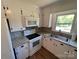 Close-up of a kitchen featuring white appliances and cabinets, plus stone-look countertops and a window at 8095 New St, Mount Pleasant, NC 28124