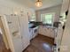 Bright kitchen with white appliances and cabinets, granite look countertops, plus wood-look floors at 8095 New St, Mount Pleasant, NC 28124