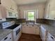 Kitchen features white cabinets and appliances, plus stone-look countertops, backsplash and floors at 8095 New St, Mount Pleasant, NC 28124