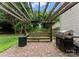 Relaxing brick back patio with pergola, outdoor lighting, built-in bench, and grill for outdoor entertainment at 8808 Palmutum Pl, Charlotte, NC 28269