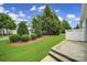 Landscaped backyard featuring well-maintained lawn, mulch beds, manicured shrubbery, and green trees at 9020 Smokey Hill Ln, Fort Mill, SC 29707