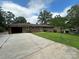 Back exterior of a brick house with a driveway, lawn, and mature trees on a partially cloudy day at 1115 Dumbarton Rd, Gastonia, NC 28054