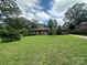 Charming brick home featuring a well-maintained lawn, mature trees, and a welcoming red front door at 1115 Dumbarton Rd, Gastonia, NC 28054
