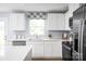 White kitchen with stainless steel appliances, quartz countertops, and a window with a modern patterned shade at 12013 Beaux Art Ln, Charlotte, NC 28214