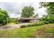 Exterior view of home with carport and chimney; lush landscaping and driveway in view at 13101 Pine Bluff Rd, Midland, NC 28107