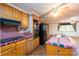 Kitchen featuring wood cabinets, black appliances, and an island with a stainless steel sink at 13101 Pine Bluff Rd, Midland, NC 28107