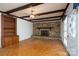 Bright living room featuring a stone fireplace, exposed beams, hardwood floors, and built in bookshelf at 13101 Pine Bluff Rd, Midland, NC 28107