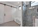 Bright bathroom featuring a glass-enclosed shower, soaking tub, and sliding barn door at 14105 Ryker Way, Davidson, NC 28036