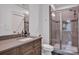 Well-lit bathroom featuring a stone-tiled shower with glass doors and a modern vanity with an integrated sink at 14105 Ryker Way, Davidson, NC 28036