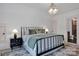 Bright bedroom showcasing a black iron bed, gray and green bedding, a patterned rug and stylish geometric light fixture at 14105 Ryker Way, Davidson, NC 28036