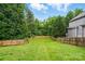 A lush green backyard is surrounded by a tall wooden privacy fence and mature trees at 14616 Pomerol Ln, Pineville, NC 28134