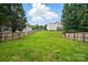A large, sloping green backyard surrounded by a wooden privacy fence and mature trees at 14616 Pomerol Ln, Pineville, NC 28134