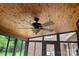 Covered ceiling fan with light fixture on wood-paneled ceiling with glass windows to the outdoor area at 1619 Bellamy Cir, Albemarle, NC 28001