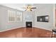 Comfortable living room featuring a cozy fireplace with a mounted TV, hardwood floors, and bright windows with shutters at 18339 The Commons Blvd, Cornelius, NC 28031