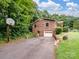 View of back exterior with a garage and parking area, surrounded by lush trees and landscaping at 1878 Pl Propst Rd, Maiden, NC 28650