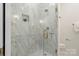 Shower featuring marble-tiled walls, gold fixtures, and a glass door at 2653 Shenandoah Ave, Charlotte, NC 28205