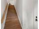 Bright, modern staircase featuring hardwood steps, white walls, and dark hardware on a white door at 2653 Shenandoah Ave, Charlotte, NC 28205