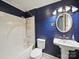 Bathroom with blue wood-paneled walls, white toilet, and a shower with a hand-held shower head at 308 W Monroe St, Salisbury, NC 28144